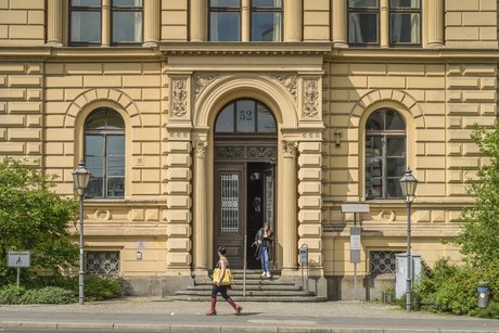 Fassade des Berliner Sozialgerichts, aus dem Eingang kommt gerade eine junge Frau. 