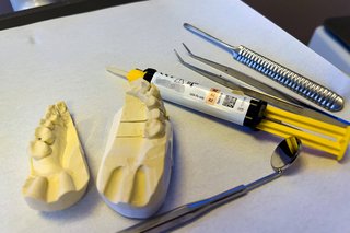 Verschiedene Utensilien eines Zahntechnikers auf einem Tablett: Ein Modell von Zähnen, verschiedene Instrumente