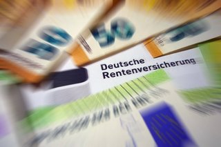 Geldscheine liegen auf einem Rentenbescheid der Deutschen Rentenversicherung 