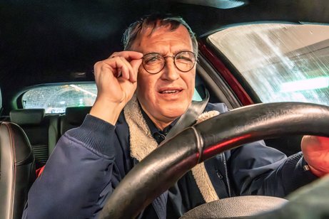 Senior am Steuer Ein älterer Mann am Steuer eines Autos. Er fasst sich an die Brille, sieht konzentriert oder überrascht aus.
