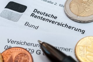 Ein Brief mit dem Briefkopf der Deutschen Rentenversicherung, darauf liegen ein Kugelschreiber und Geldmünzen 