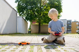 Kind spielt im Freien mit einem ferngesteuerten Spielzeugauto