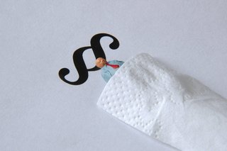 Ein kleines Figürchen liegt auf einem Paragraphen-Zeichen und ist mit einem Taschentuch zugedeckt wie mit einer Bettdecke