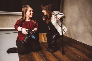 Fotografin Anna Spindelndreier kniet während einer Fotosession neben einer jungen Frau. Sie unterhalten sich, lachen. 