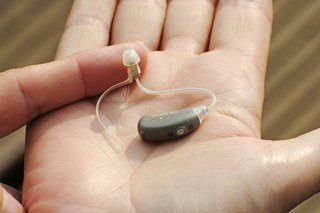 Modernes, kleines Hörgerät in der Hand einer Frau