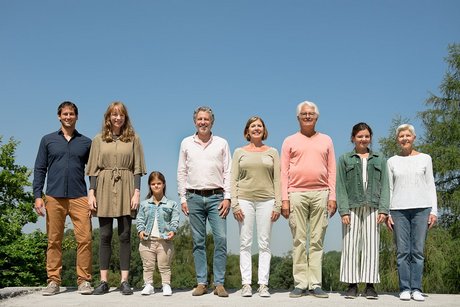 Menschen verschiedenen Alters, mit und ohne Behinderung, stehen lächelnd nebeneinander.