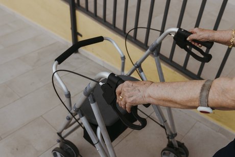 Eine Seniorin hält die Griffe eines Rollators.