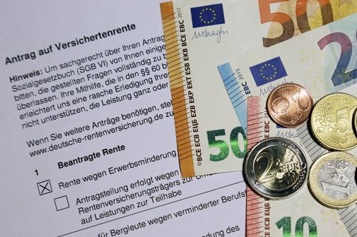 Ein Antrag auf Erwerbsminderungsrente. Darauf liegen Euro-Scheine und -M&uuml;nzen.