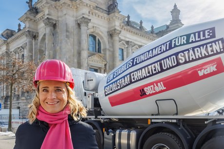 VdK-Präsidentin Verena Bentele vor dem Bundestag, neben ihr ein großer Betonmischer mit der Aufschrift "Ein starkes Fundament für alle: Sozialstaat erhalten und stärken!"