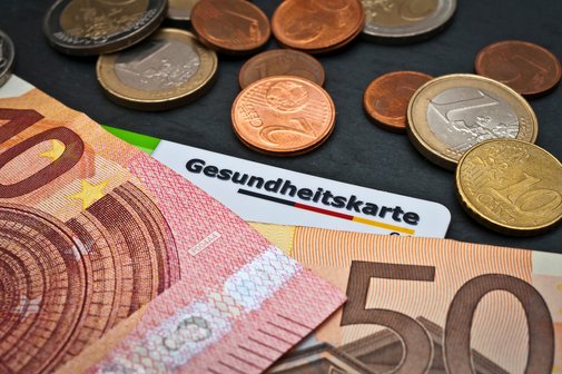 Geldscheine und Münzen, darunter liegt eine Gesundheitskarte.