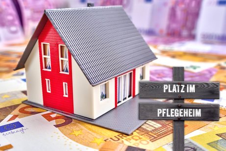 Kosten im Pflegeheim Die Bildmontage zeigt ein Spielzeug-Gebäude, das auf Geldscheinen steht. Davor ein kleiner Wegweiser mit der Aufschrift "Platz im Pflegeheim"