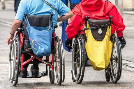 Zwei Rollstuhlfahrer fahren nebeneinander in der Münchner Innenstadt