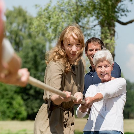 Ältere Frau, jüngere Fau und jüngerer Mann ziehen an einem Tau.