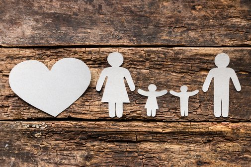 Familie Eine aus Papier ausgeschnittene Familie mit Vater, Mutter und zwei Kindern auf hölzernem Untergrund