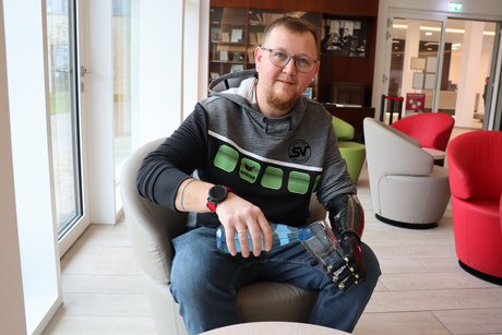 Dominik Müller hält mit seiner Handprothese ein Glas.