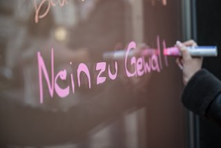 Auf einem Schaufenster steht in rosafarbener Schrift: Nein zu Gewalt.