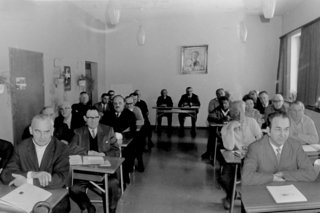 Auf dem Foto sieht man ehrenamtlichen Mitarbeiter des VdK in der Nachkriegszeit, die in einem Schulungsraum sitzen.