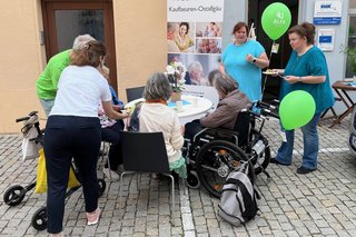 Auf dem Foto sieht man Mitarbeitende der VdK-Kreisgeschäftsstelle Kaufbeuren-Ostallgäu und Besucherinnen und Besucher an einem Tisch in der Altstadt von Kaufbeuren.