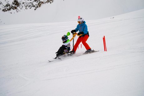 Auf dem Foto sieht man einen Biski-Teilnehmer in Begleitung auf der Piste.