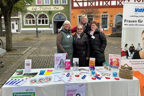 Vier Mitarbeiterinnen stehen an einem Infostand zum Thema "Gewalt gegen Frauen" auf dem Neust&auml;dter Marktplatz. 