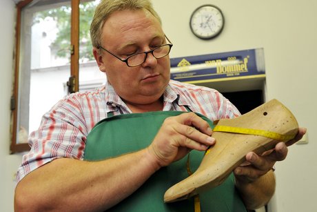 Ein Schuster fertigt einen orthopädischen Maßschuh an.