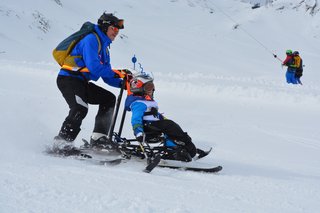 Auf dem Foto sieht man einen Biski-Teilnehmer in Begleitung auf der Piste.