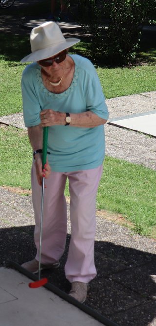 Eine ältere Dame beim Minigolf spielen