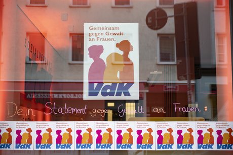 Schaufenster der VdK-Landesgeschäftsstelle. Es hängt ein großes und viele kleine Plakate zum Aktionstag "Gegen Gewalt an Frauen" am Fenster.