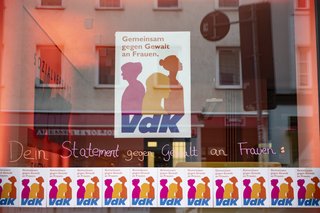 Schaufenster der VdK-Landesgeschäftsstelle. Es hängt ein großes und viele kleine Plakate zum Aktionstag "Gegen Gewalt an Frauen" am Fenster.