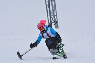 Auf dem Foto sieht man ein junges Mädchen Bi-Ski-Fahren.