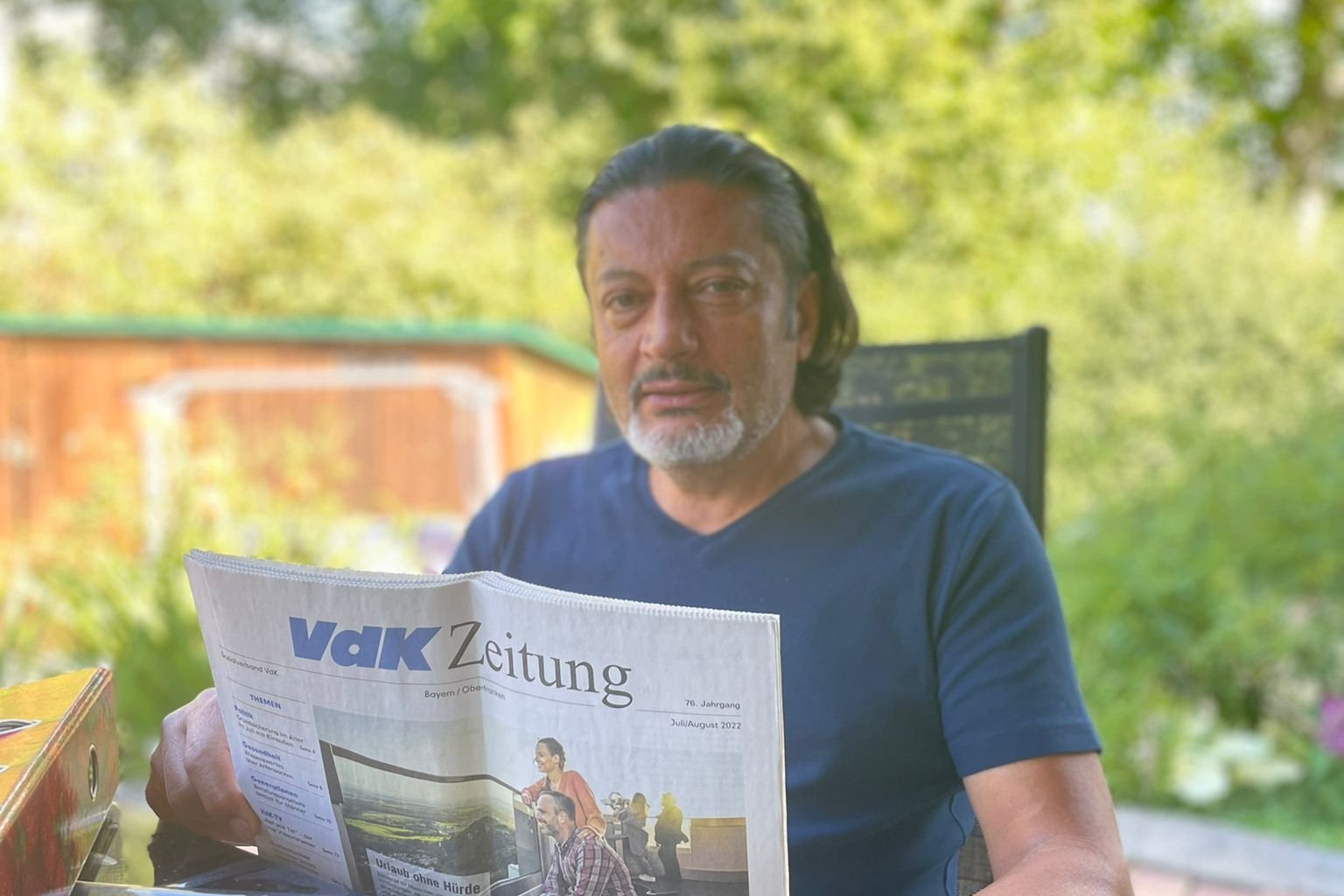 Selim Toksöz beim Lesen der VdK-Zeitung in einem Garten.