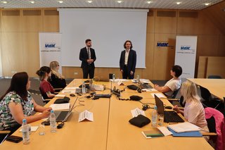 Auf dem Foto sieht man den Leiter der Rechtsabteilung im VdK Bayern, Daniel Overdiek (stehend rechts), und den Fachreferent für Aus- und Weiterbildung, Marin Stimac (links neben ihm), mit neuen VdK-Mitarbeiterinnen, die um einen großen Tisch herum sitzen.