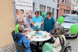 Auf dem Foto sieht man Mitarbeitende der VdK-Kreisgeschäftsstelle Kaufbeuren-Ostallgäu und Besucherinnen und Besucher an einem Tisch in der Altstadt von Kaufbeuren.