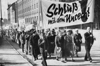 Auf dem Foto sieht man VdK‐Mitglieder in der Bundeshauptstadt Bonn 1963. Sie demonstrieren gegen die unzureichende Versorgung der Kriegsopfer. Das Foto ist schwarz-weiß.
