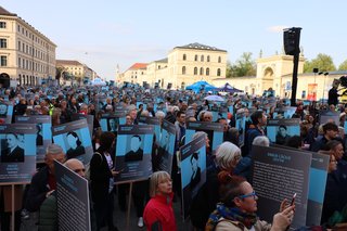 Auf dem Foto sieht man die Teilnehmenden des BR-Projekts auf dem Odeonsplatz. Viele halten Schilder mit den Namen und Biografien von Münchnerinnen und Münchnern in der Hand, die Opfer des NS-Regimes wurden.