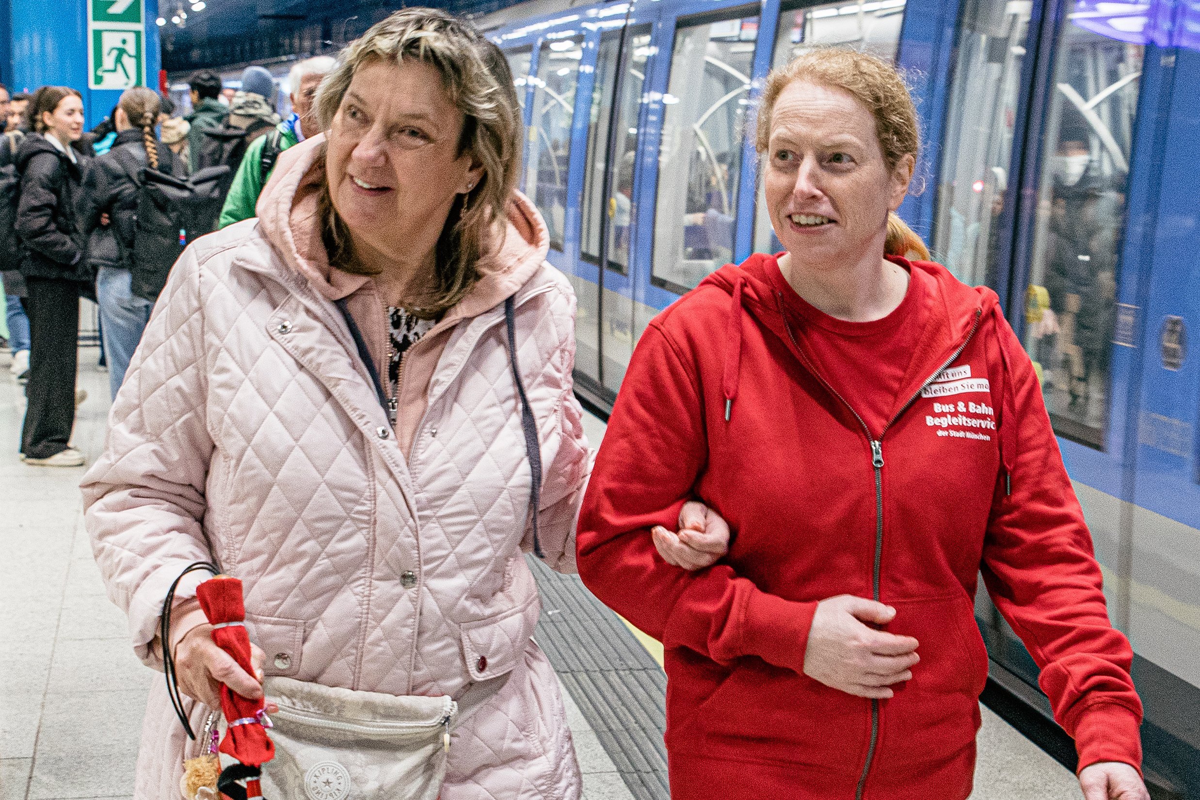 Eine Mobilit&auml;tsbegleiterin (rechts) begleitet eine Frau auf Kr&uuml;cken.