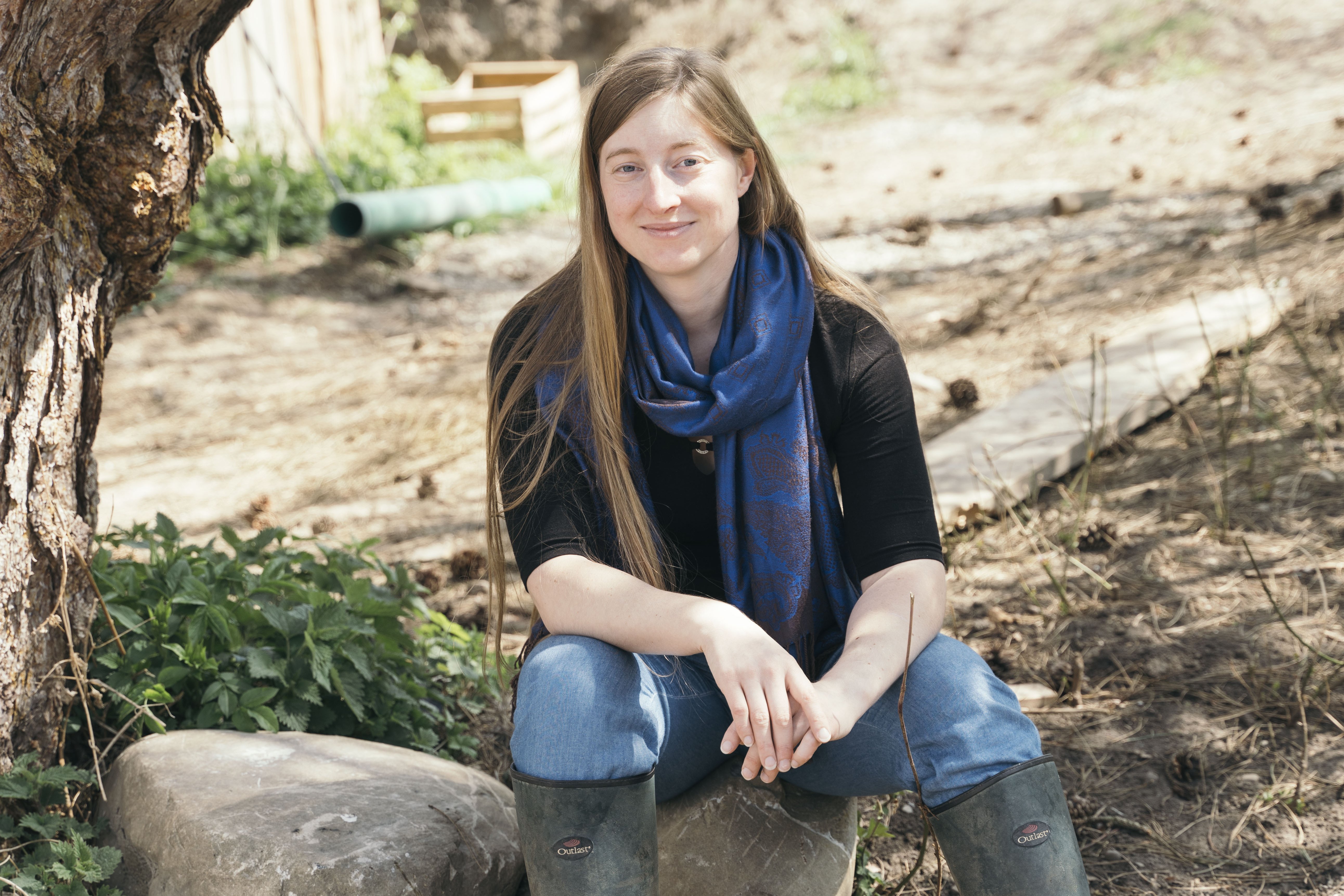 Das Foto zeigt Stefanie Bremer. Sie sitzt auf einem Baumstamm und lächelt in die Kamera.