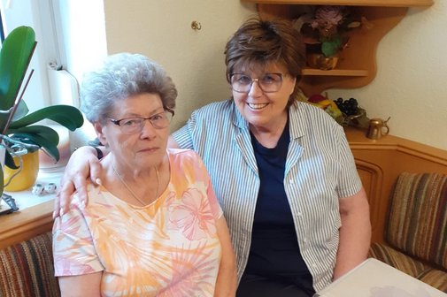 VdK-Pflegebegleiterin Anna Fischer (links) sitzt neben Brigitte Hörber, um die sie sich kümmert.