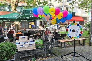 Kleiner VdK-Info-Stand mit bunten Luftballons, weißen VdK-Stofftaschen und einem Glücksrad mit Aufdruck VdK Ortsverband Nürnberg-Süd