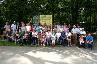 Eine Gruppe Menschen mit vielen Kindern vor dem Willkommensschild des Tiergartens