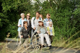 Das Foto zeigt eine Gruppe an Menschen mit und ohne Behinderung bei einem Spaziergang durch einen Park.
