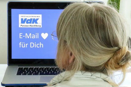 Frau sitzt am Bildschirm und erhält eine Mail vom VdK