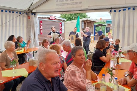 G&auml;ste sitzen an Biertischen im Festzelt