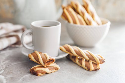 In der Mitte steht eine Tasse Kaffee. Rechts daneben steht eine Sch&uuml;ssel mit Keksen. Vor der Tasse Kaffee liegen ebenfalls Kekse.