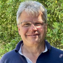 Christian Wirth l&auml;chelnd vor gr&uuml;nem Geb&uuml;sch