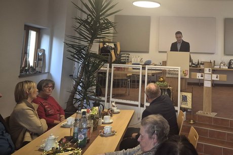 Der B&uuml;rgermeister steht an einem Redepult und h&auml;lt eine Rede vor dem Publikum im Saal.