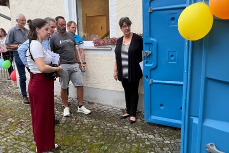 Menschengruppe vor geöffneter mobiler barrierefreier Toilette