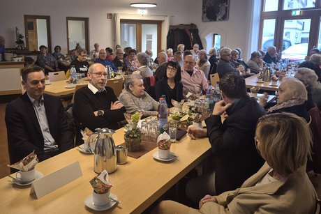 VdK-Mitglieder und G&auml;ste sitzen an Tischen in einem Saal und unterhalten sich