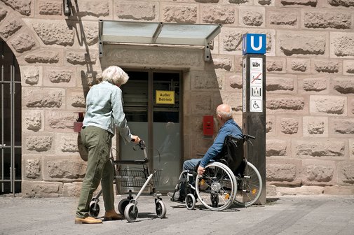 Barrieren im ÖPNV Eine Seniorin mit Rollator und ein Senior im Rollstuhl stehen am unzugänglichen Eingang einer U-Bahn-Station. Dort ist ein Aufzug mit dem Hinweis "Außer Betrieb".