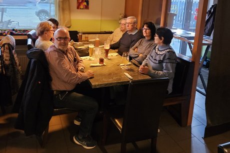 7 Personen sitzen am Tisch und warten auf den Hering